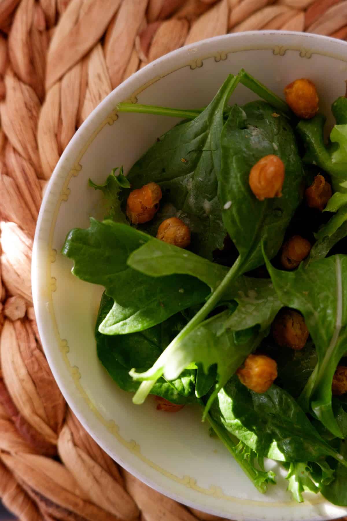 bowl of modern Caesar salad in china bowl, topped with eggless dressing and crunchy chickpeas