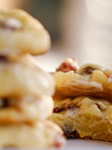 two in-focus iced orange rum raisin cookies, one with big bite missing