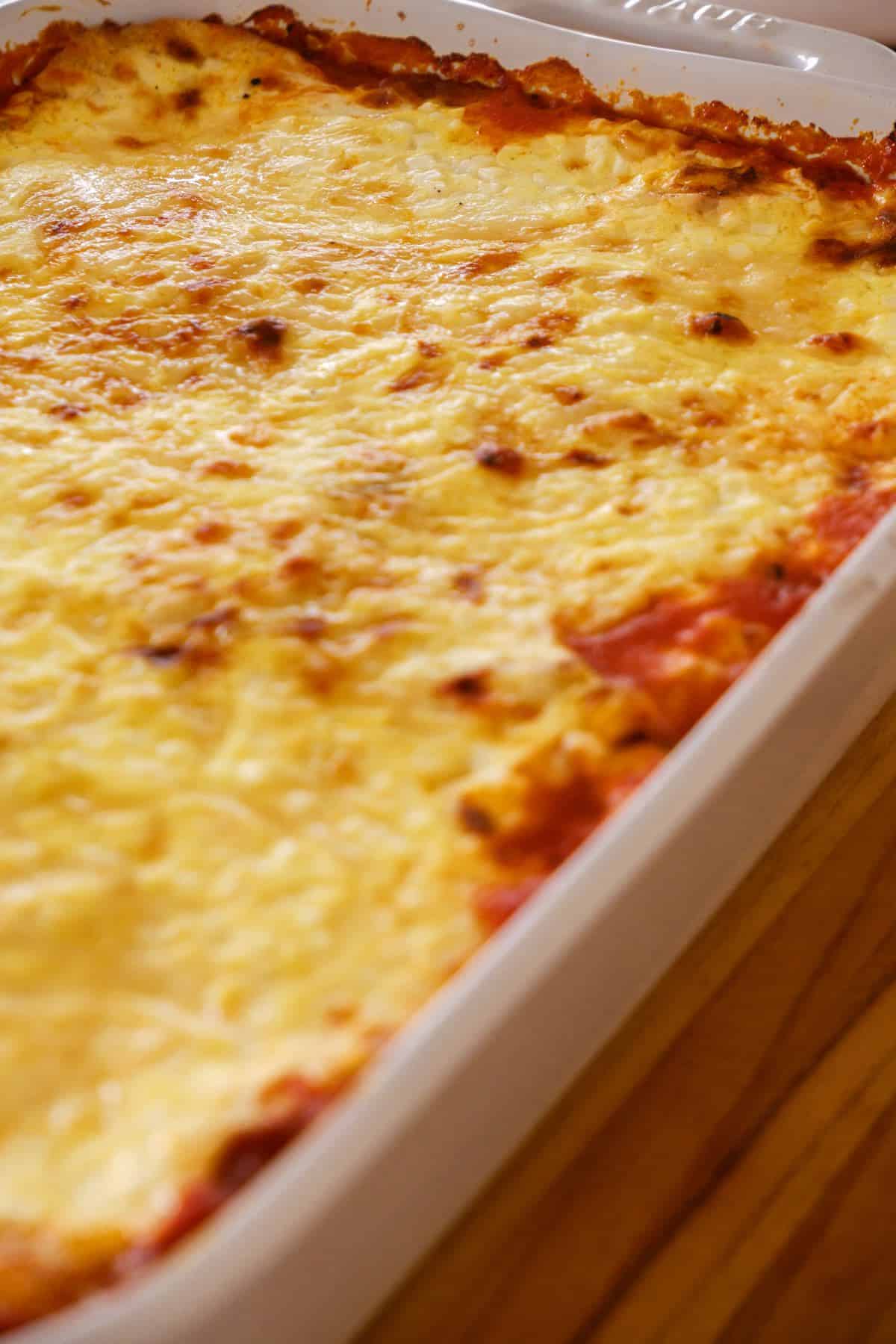 Big white pan of lasagna on wood surface