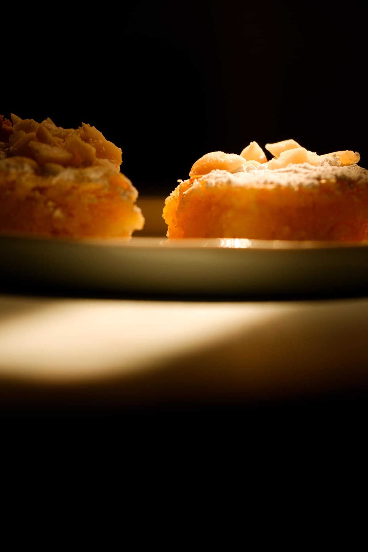 2 lemon squares at eye level on a plate in dramatic sun beam