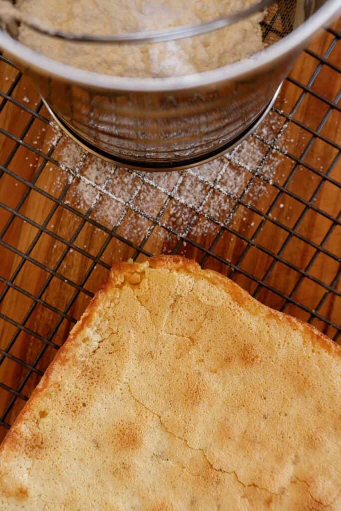 baked lemon squares uncut, next to powder sugar sifter