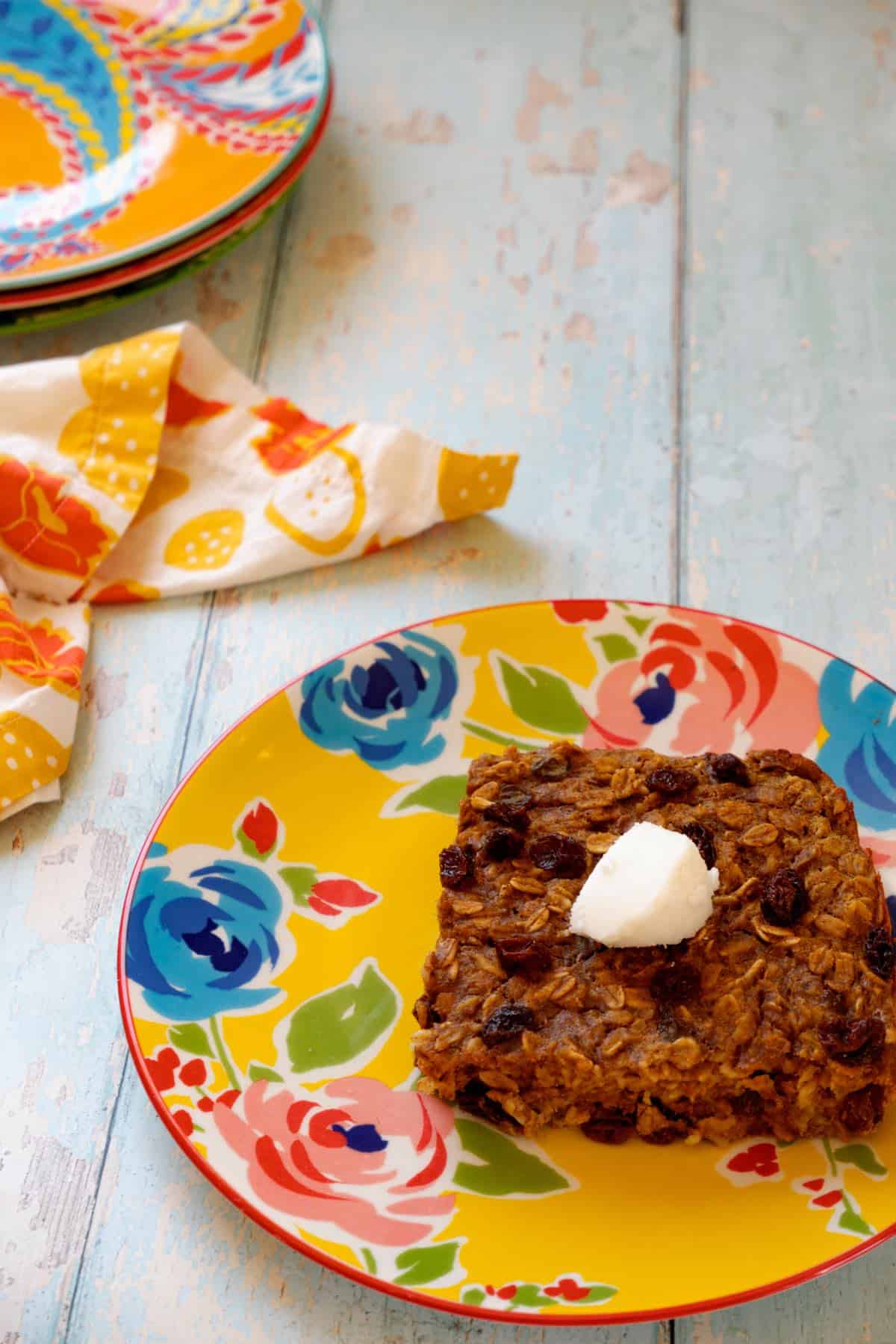 square of pumpkin protein baked oats topped with coconut butter on flowered yellow plate