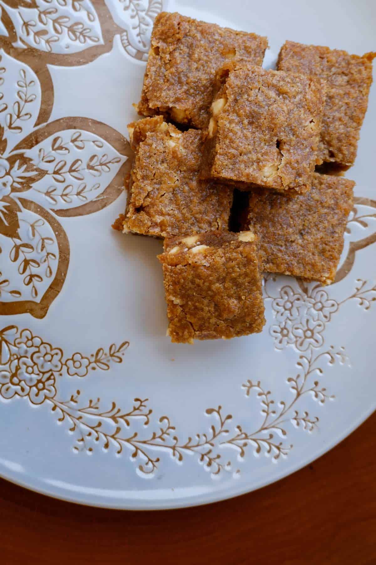 6 bourbon white chocolate brownies stacked on a blue and gold plate